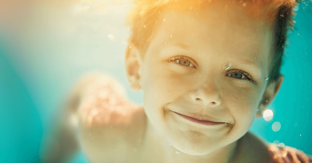 boy swimming underwater with eyes open in a clean swimming pool